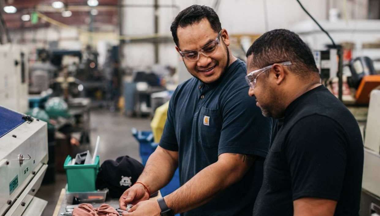 two manufacturing trainees talking in a manufacturing workshop