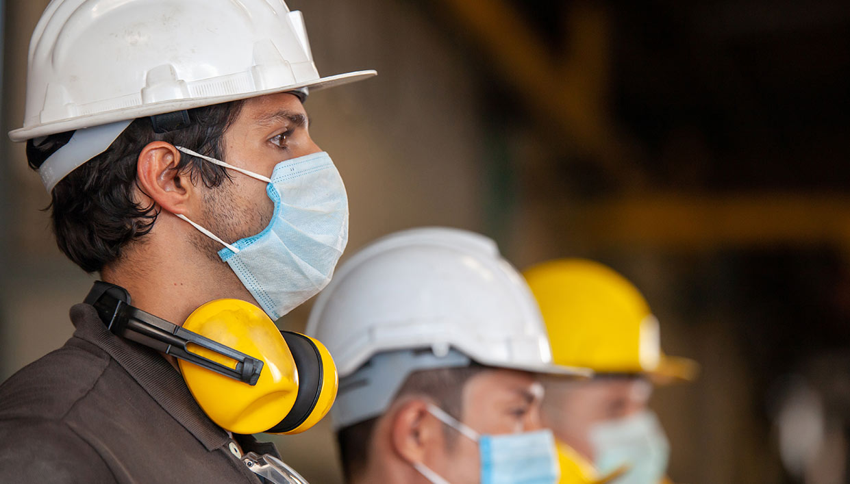 manufacutring employees standing in a line wearing face masks
