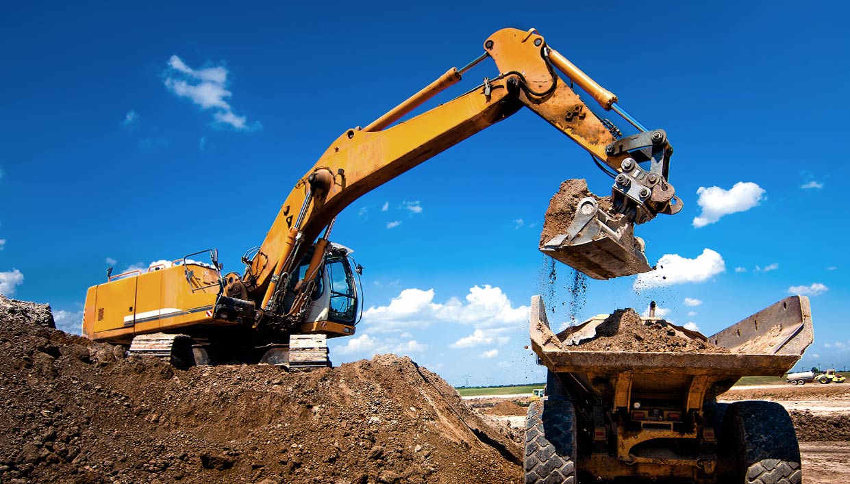 earth mover loading dirt into a dump truck